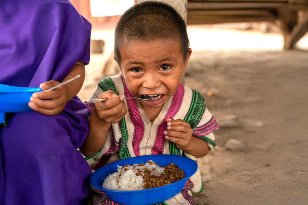 little boy eating rice and beans