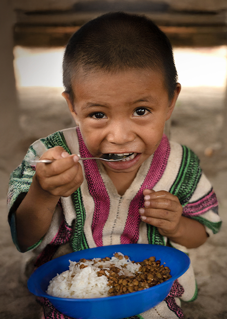 little boy eating bowl of rice