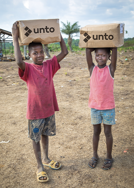 kids holding Unto boxes full of aid